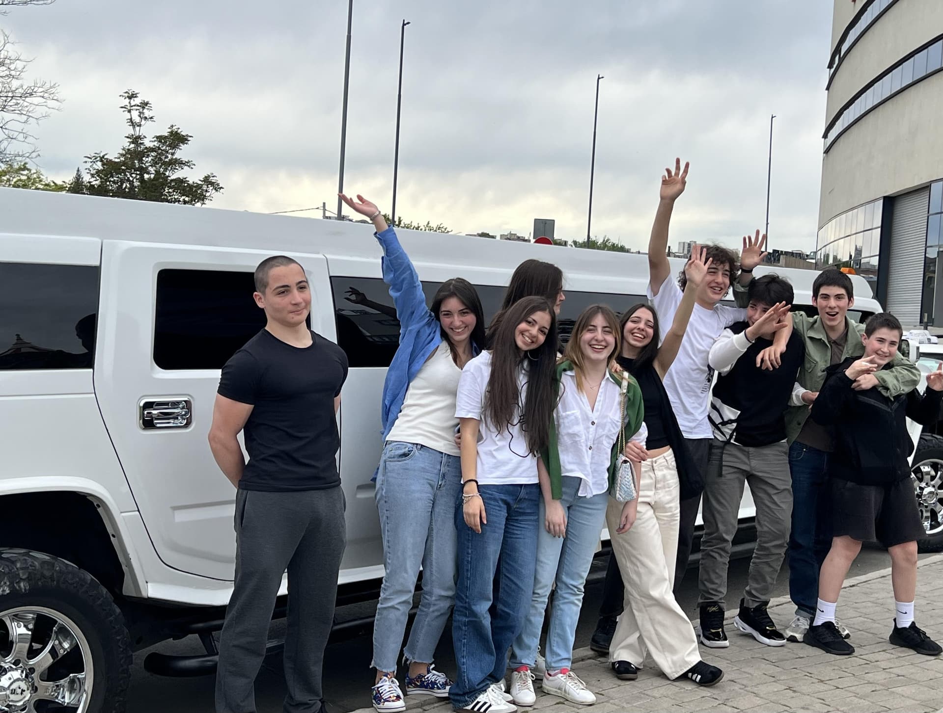Group of friends beside a white Hummer stretch limousine
