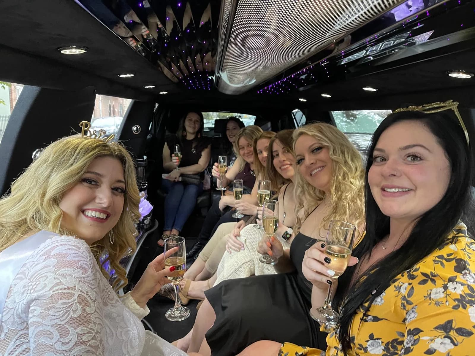 Bachelorette party guests celebrating with champagne inside a stretch limousine with a starlight ceiling.