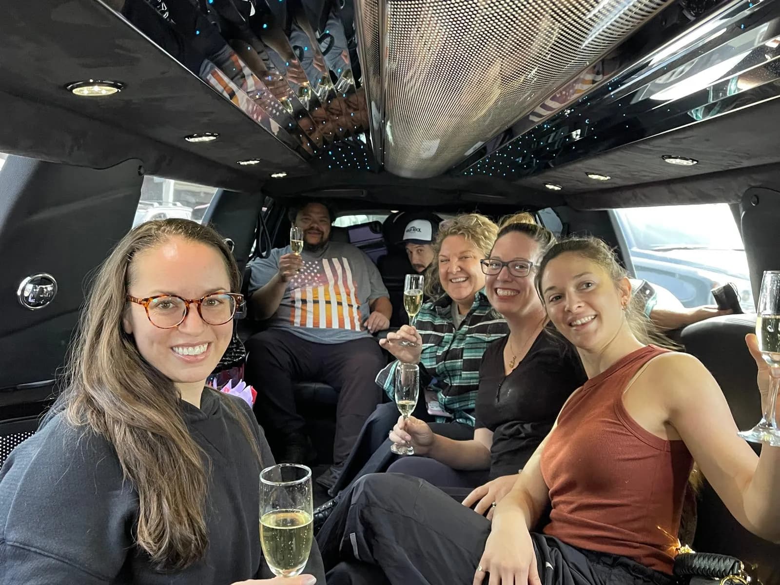 Friends raising champagne glasses inside a stretch limousine
