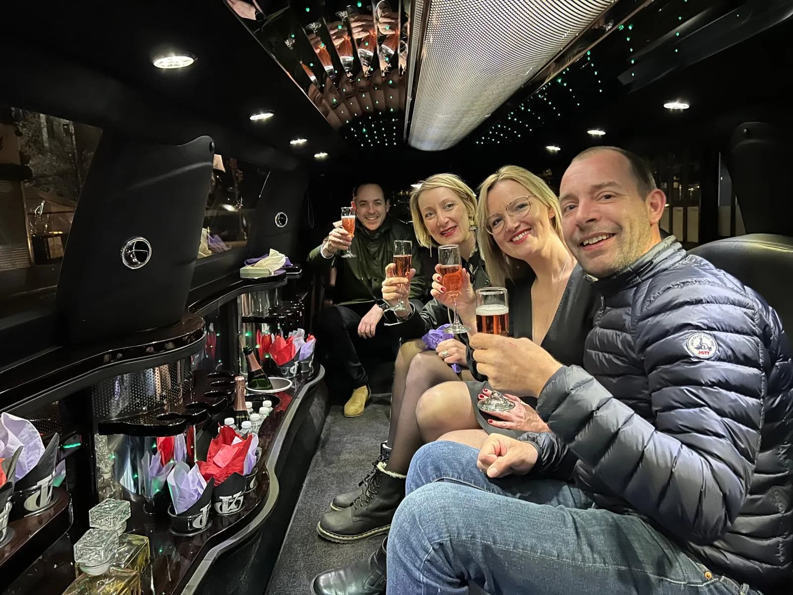 Friends enjoying drinks at the lit bar of a stretch limousine