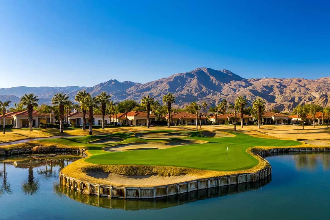 Golf course green ringed by water and palm trees