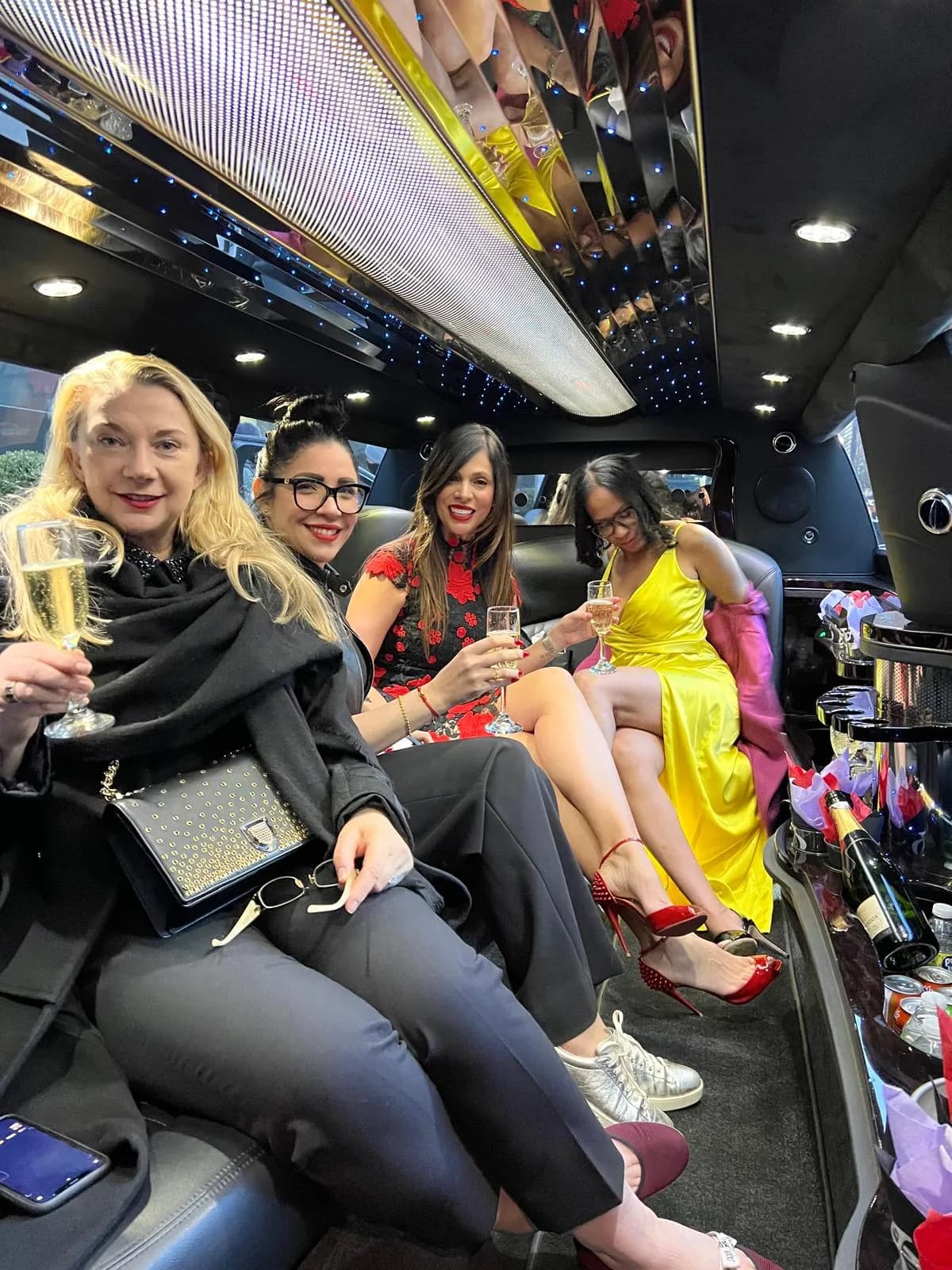 Guests in evening dresses with champagne at the stretch limousine bar