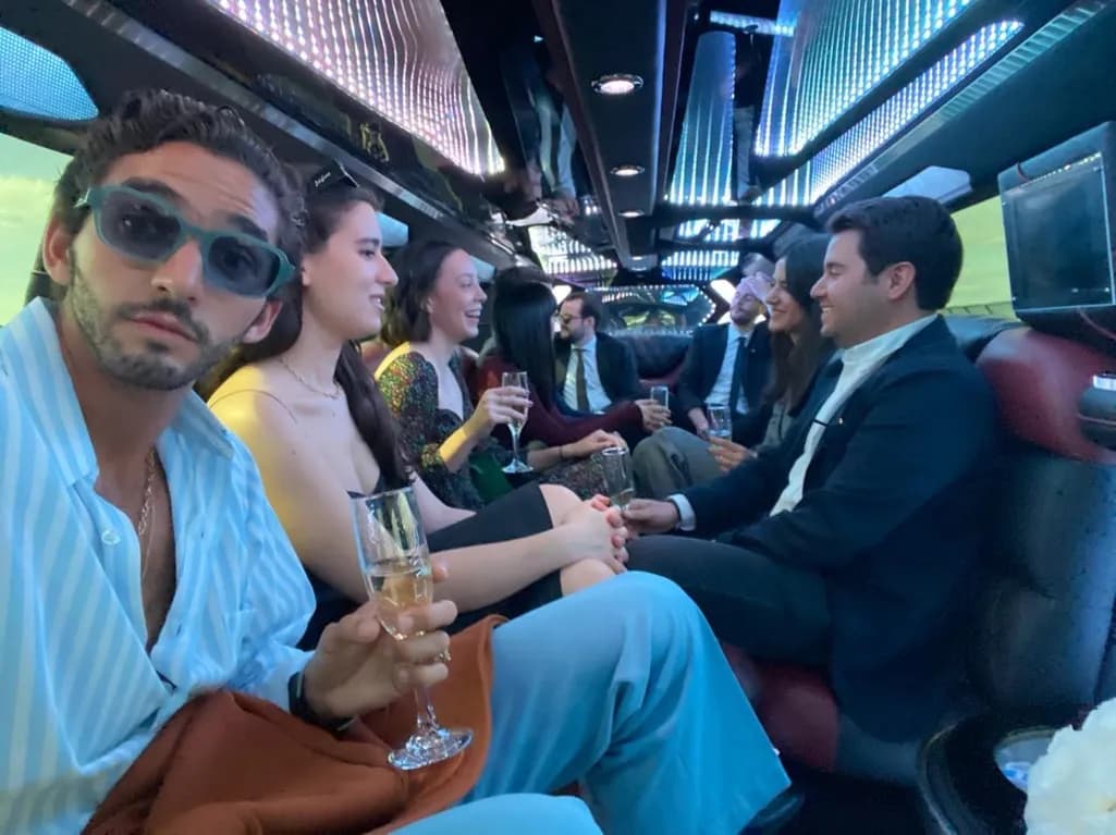 Guests enjoying champagne inside a NYC party bus featuring colorful LED ceiling lighting.
