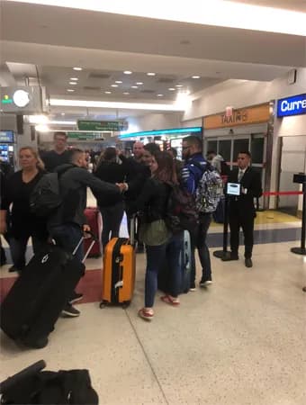 King & Queen Limo chauffeur providing meet-and-greet service at a NYC airport and assisting arriving passengers with luggage.