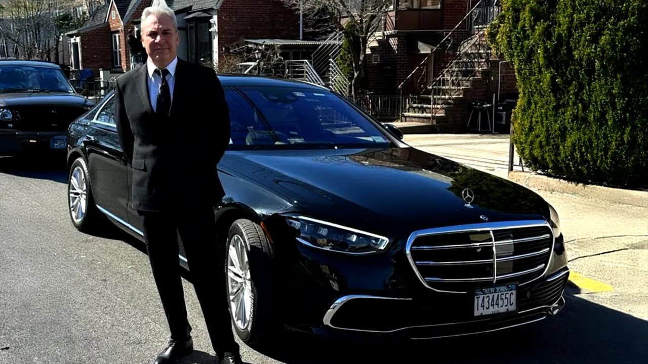 Chauffeur standing beside a black Mercedes S-Class sedan