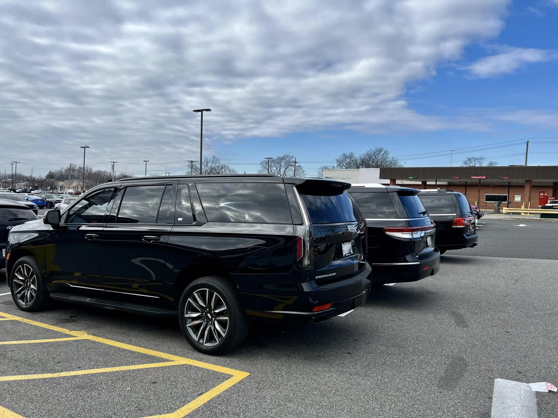 Black Cadillac Escalade and Chrysler Pacifica parked in a row at a plaza
