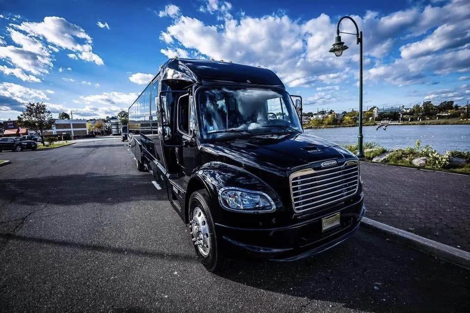Black Freightliner executive shuttle bus parked along the harbor
