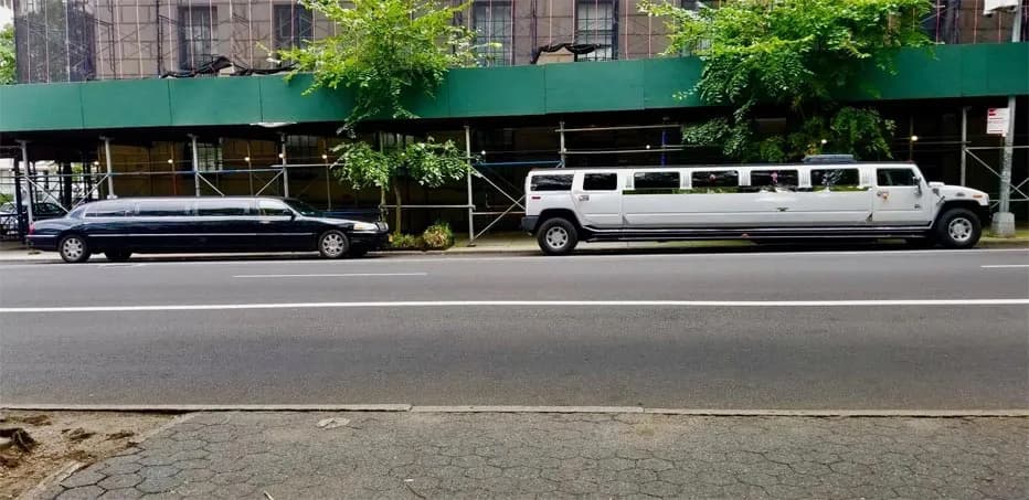 White Hummer stretch limousine and black Lincoln limo parked on a city street