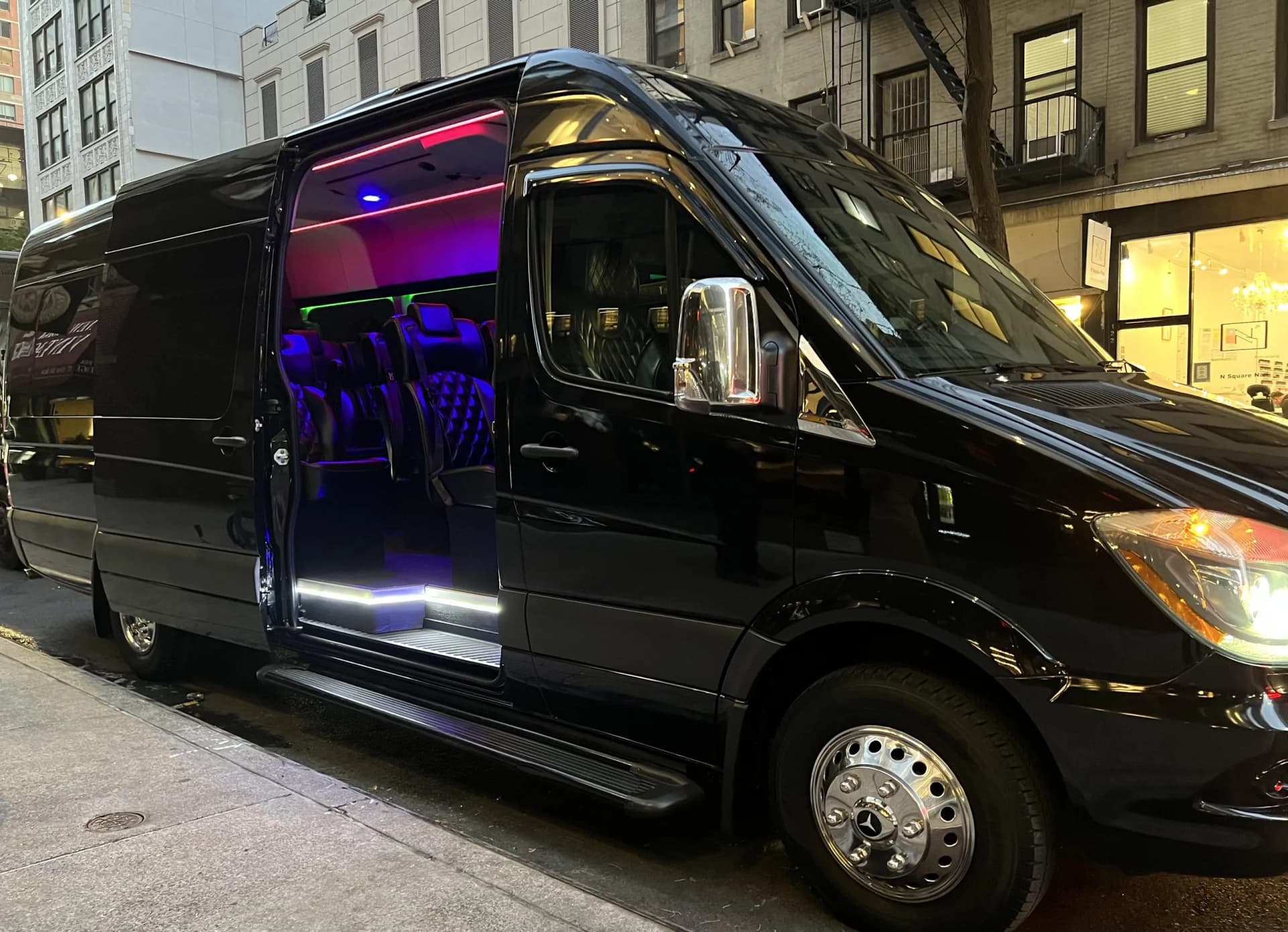 Black Sprinter limo van with the door open showing purple LED lighting