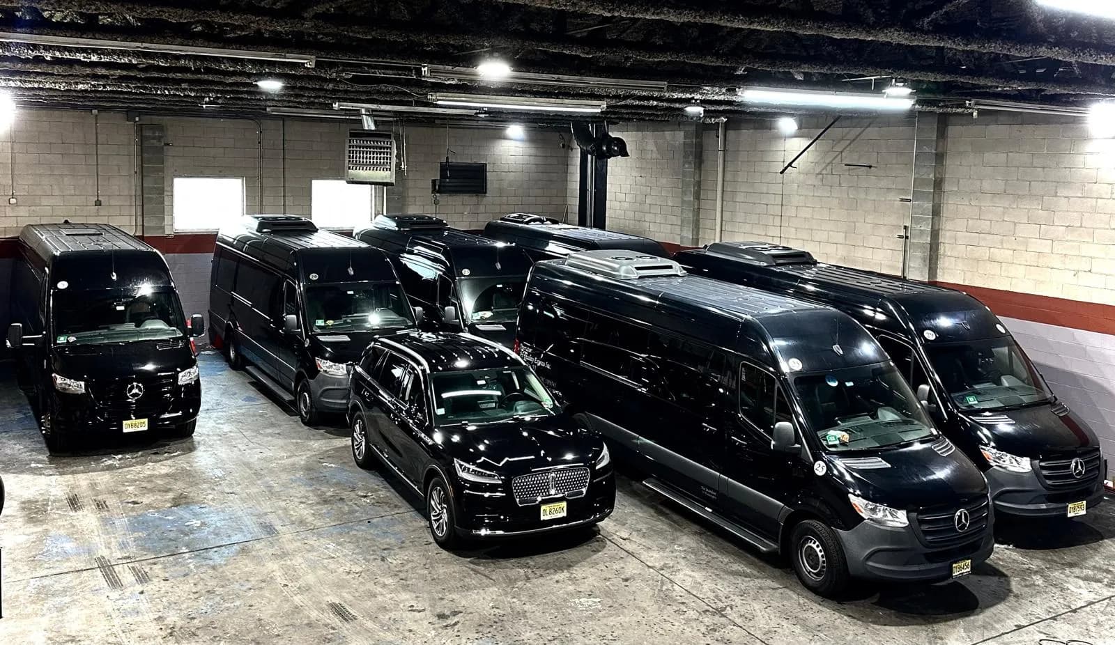 Fleet of black Mercedes Sprinter vans and a Lincoln Navigator in the garage