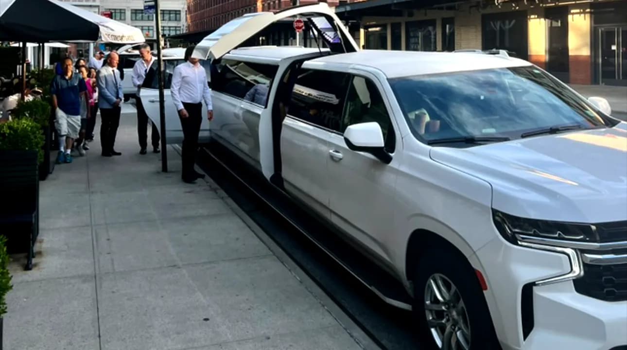 Guests boarding a white Chevrolet Suburban stretch limousine with jet doors in NYC