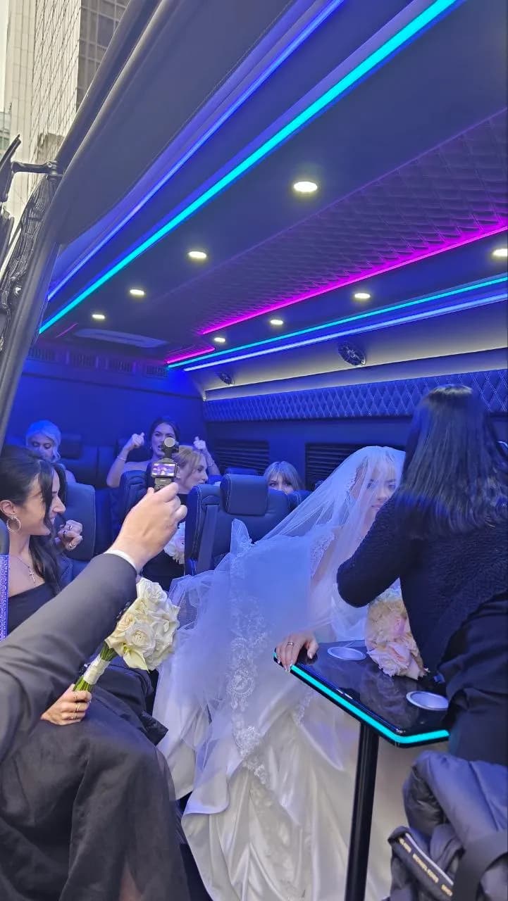 Bride seated inside a King & Queen Limo wedding party bus featuring colorful LED lighting.
