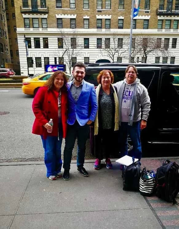 Chauffeur with a family beside a black SUV on a Manhattan pickup