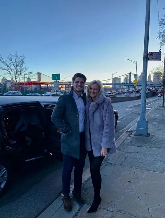 Couple beside their black SUV near the bridges of Lower Manhattan at dusk