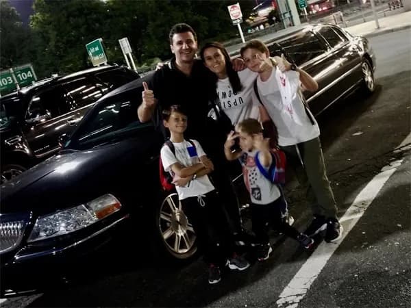Family posing with their black stretch limousine before the game