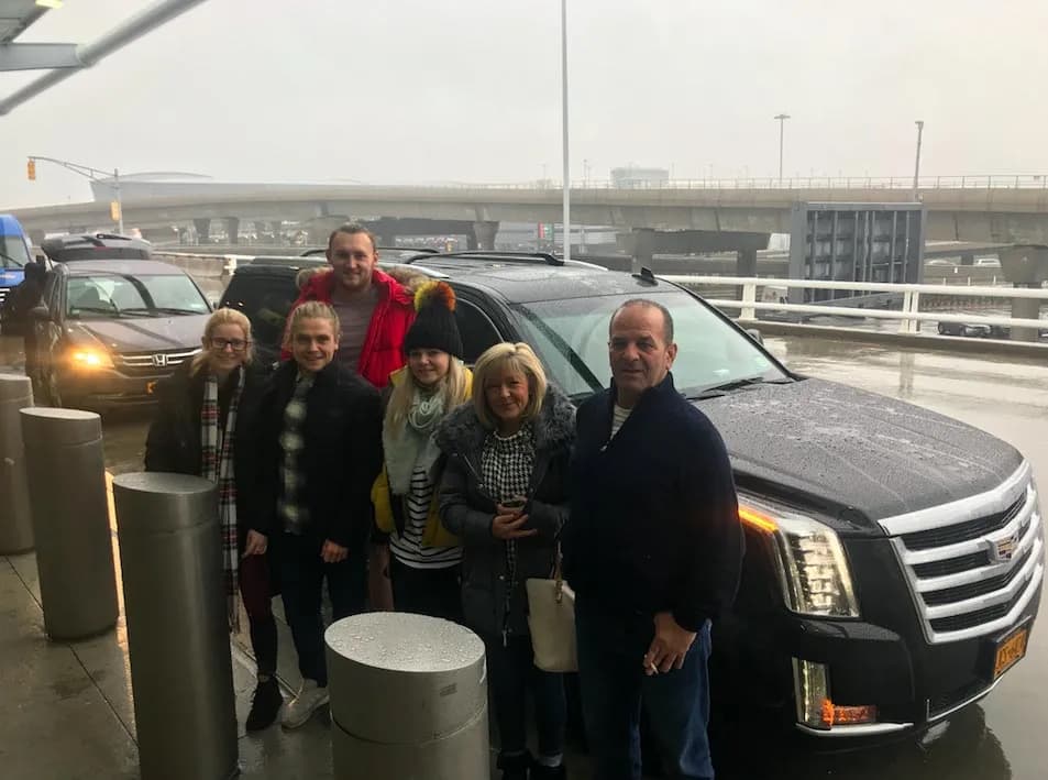 Family beside a black Escalade at the JFK terminal curb