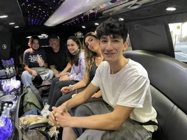 Family of five smiling in the back of the stretch limo in the city
