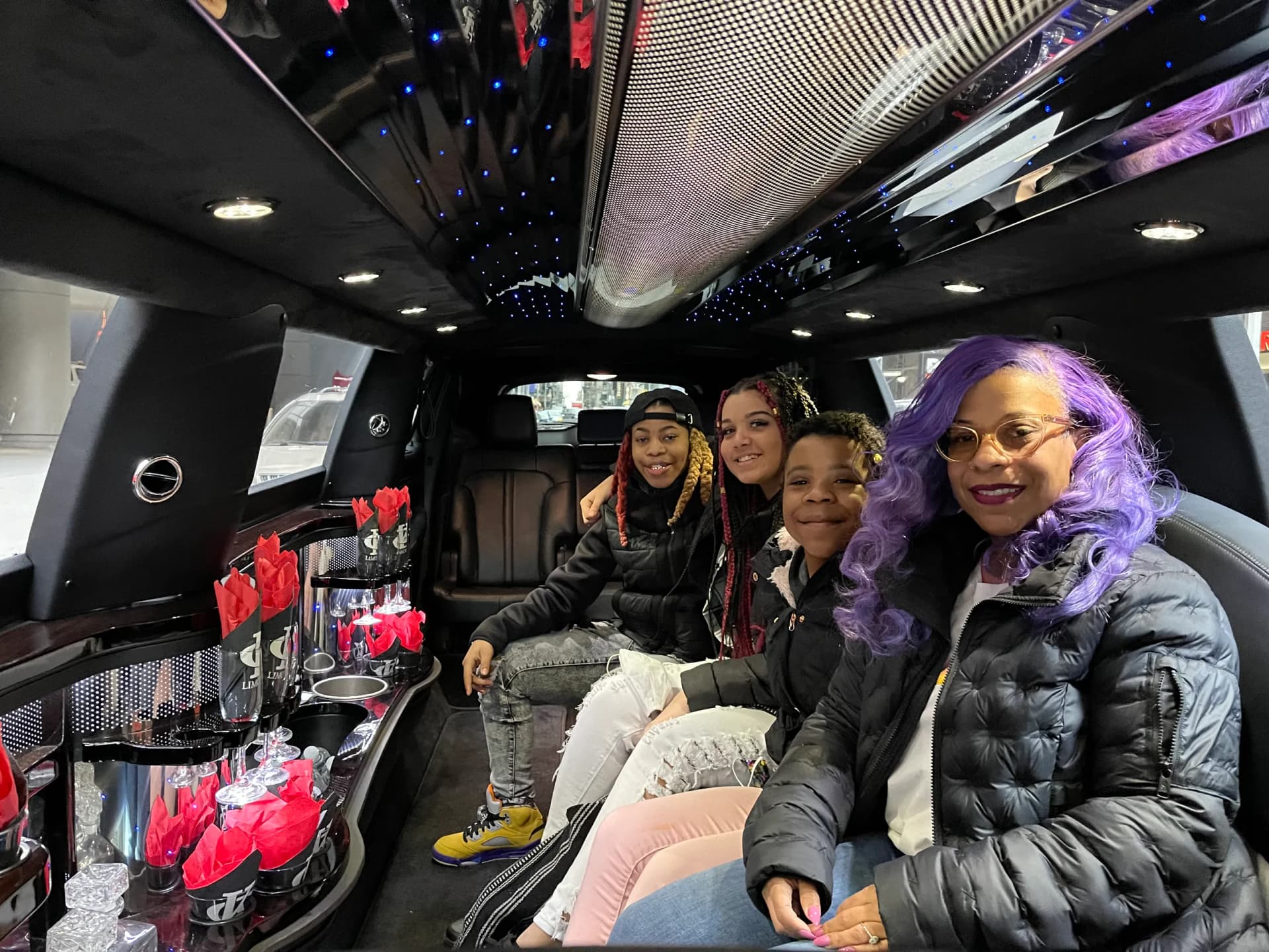 Family riding a stretch limo with starlight ceiling and red roses on the bar