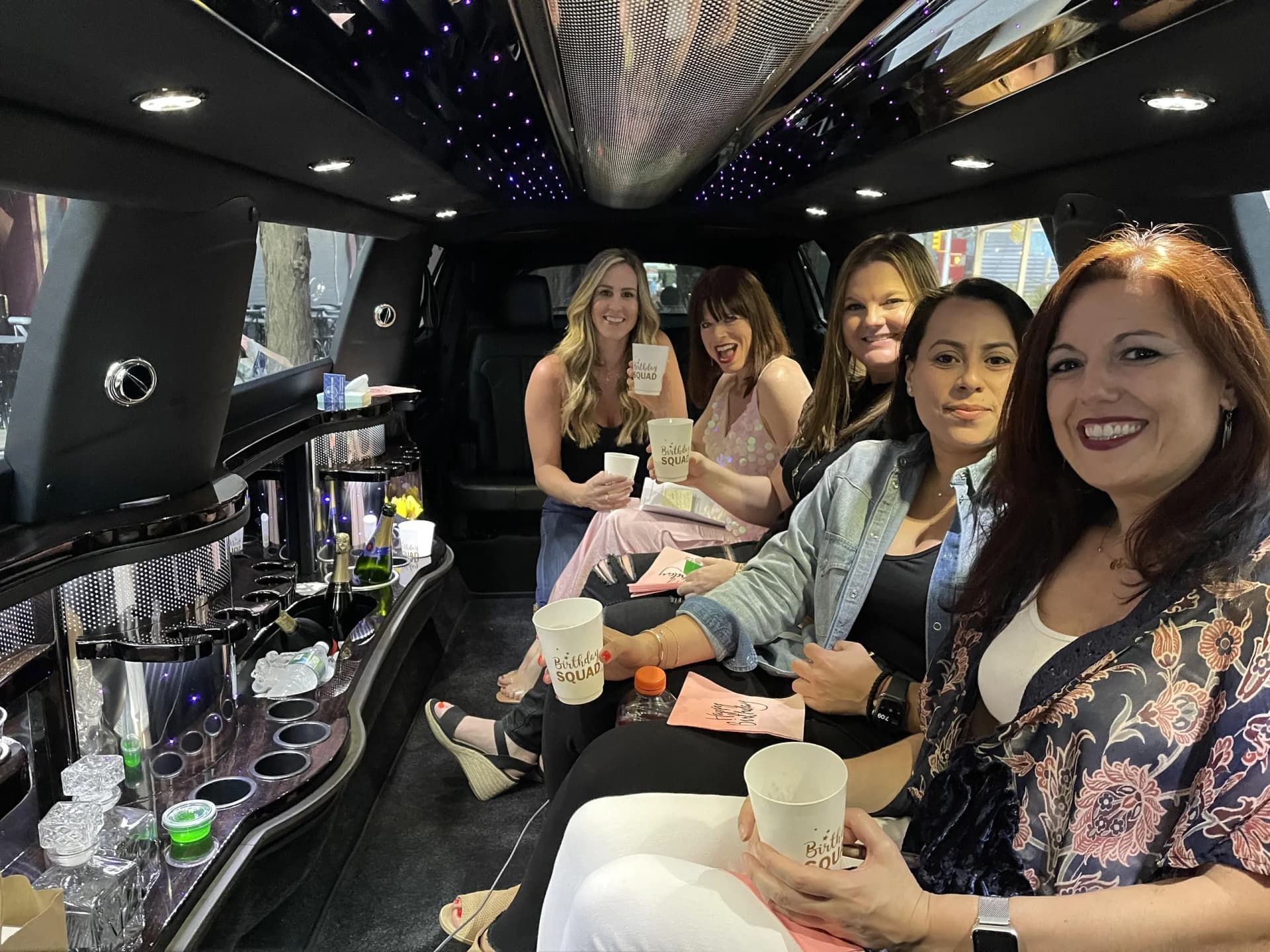 Friends enjoying drinks inside a stretch limousine on a sightseeing tour