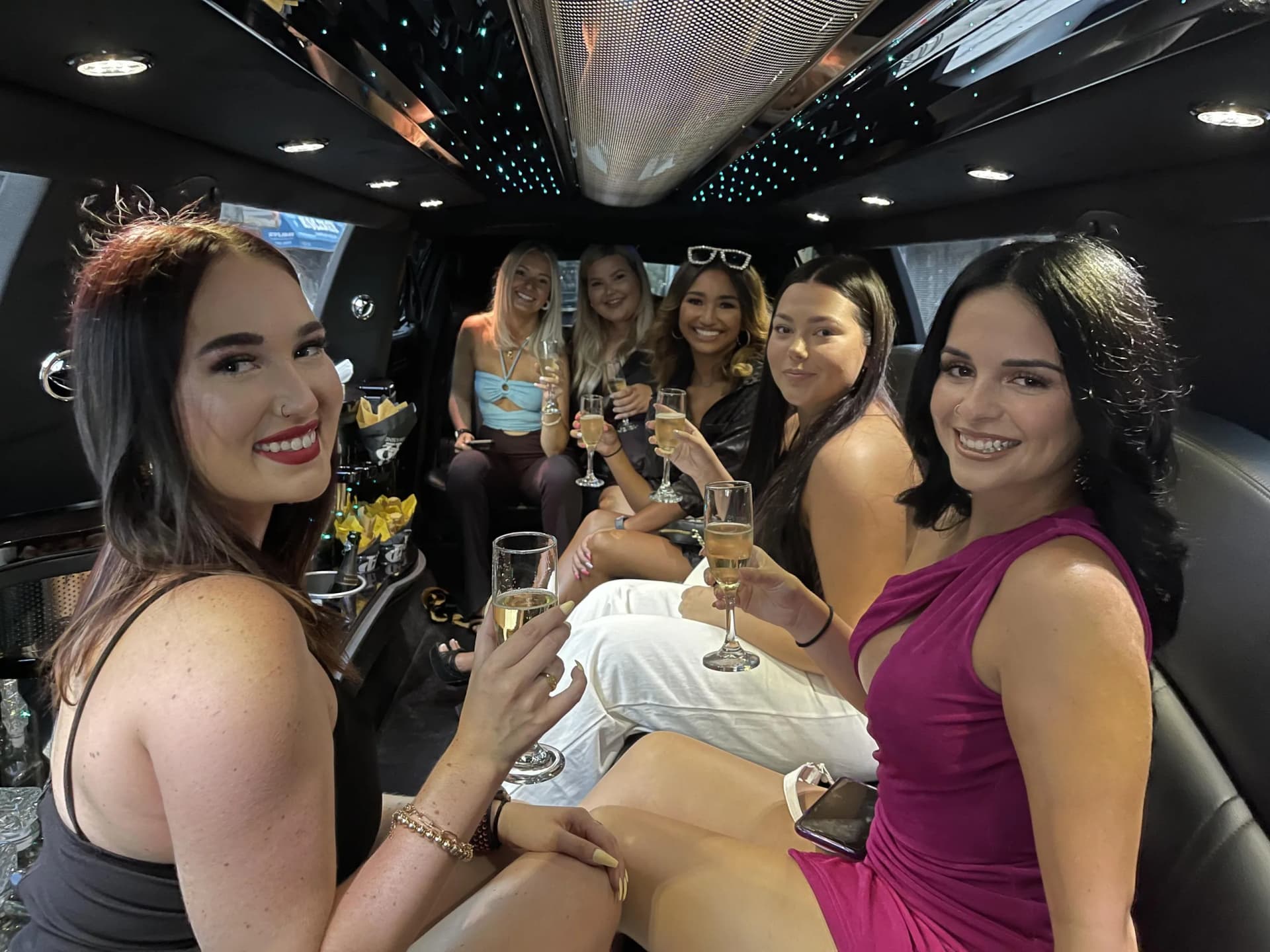 Six friends toasting champagne inside the stretch limousine