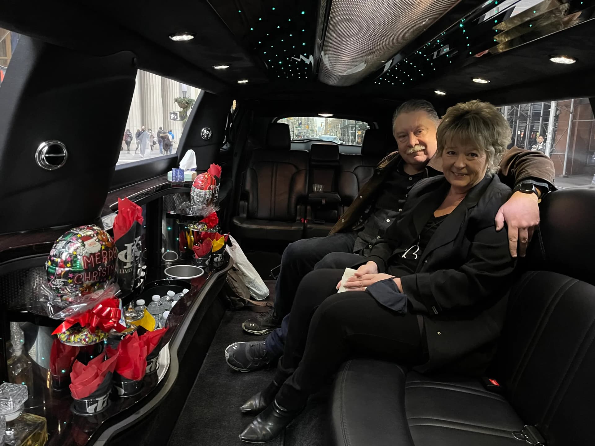 Couple enjoying a holiday lights limo ride with snacks and festive balloons