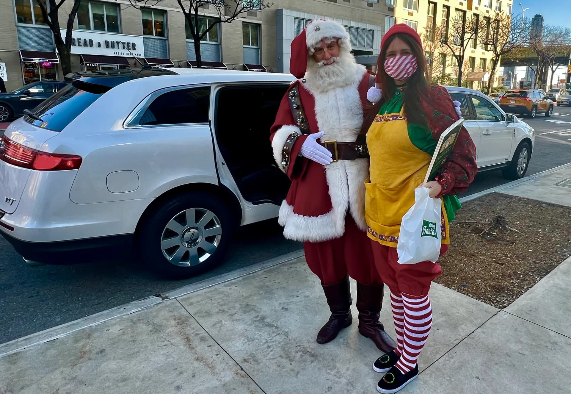 Santa Claus and an elf beside a white Lincoln limousine in Manhattan