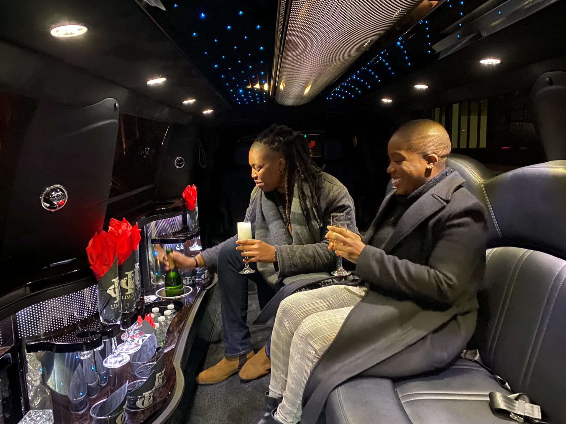 Passengers pouring champagne at the bar inside a King & Queen Limo stretch limousine in NYC.