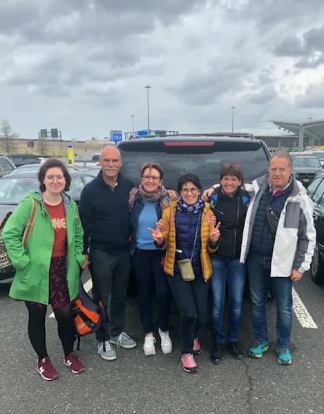 Tour group posing behind their SUV after an airport pickup