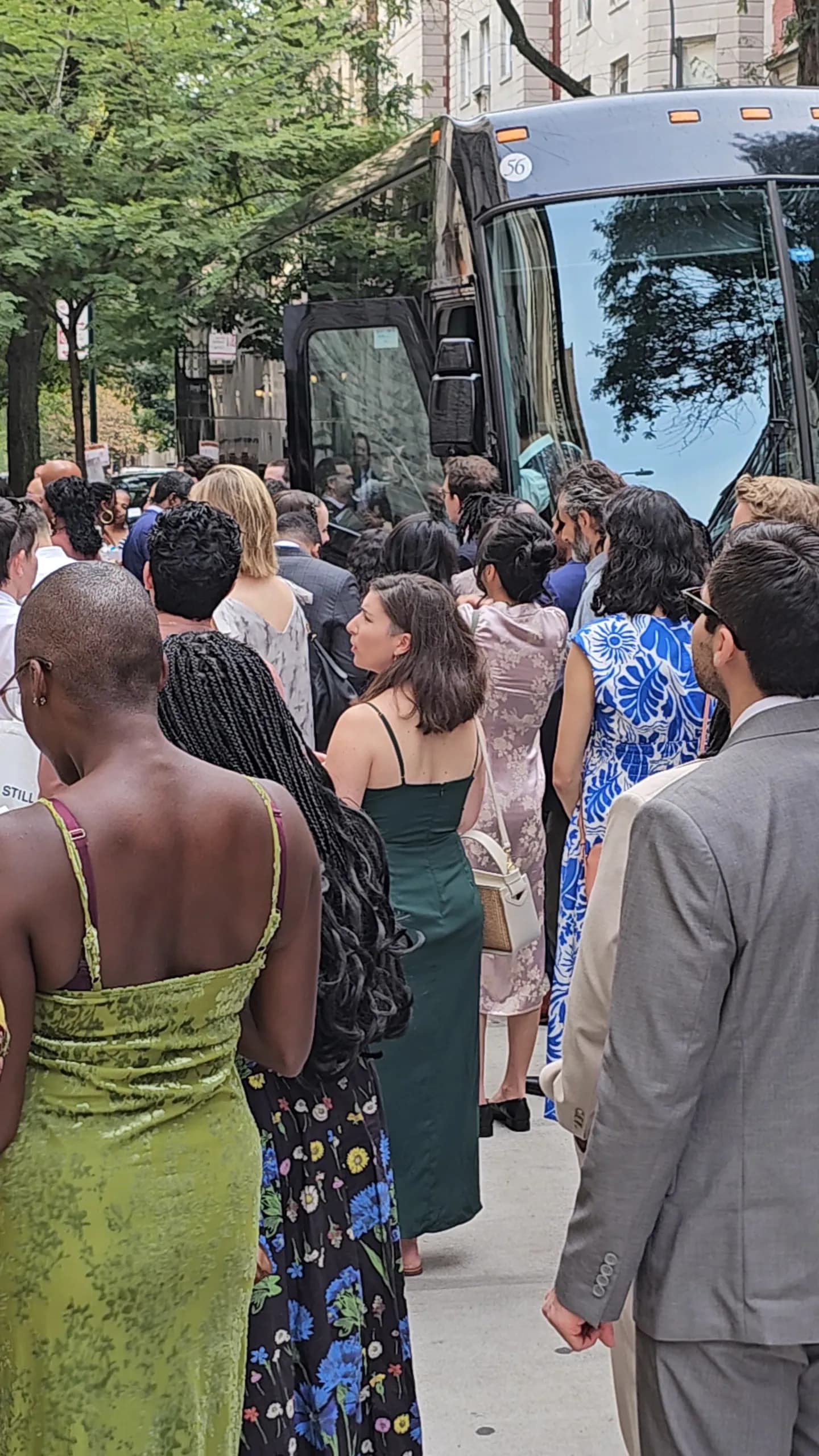 Wedding guests in formal attire preparing to board a private 56-passenger coach bus in Manhattan.