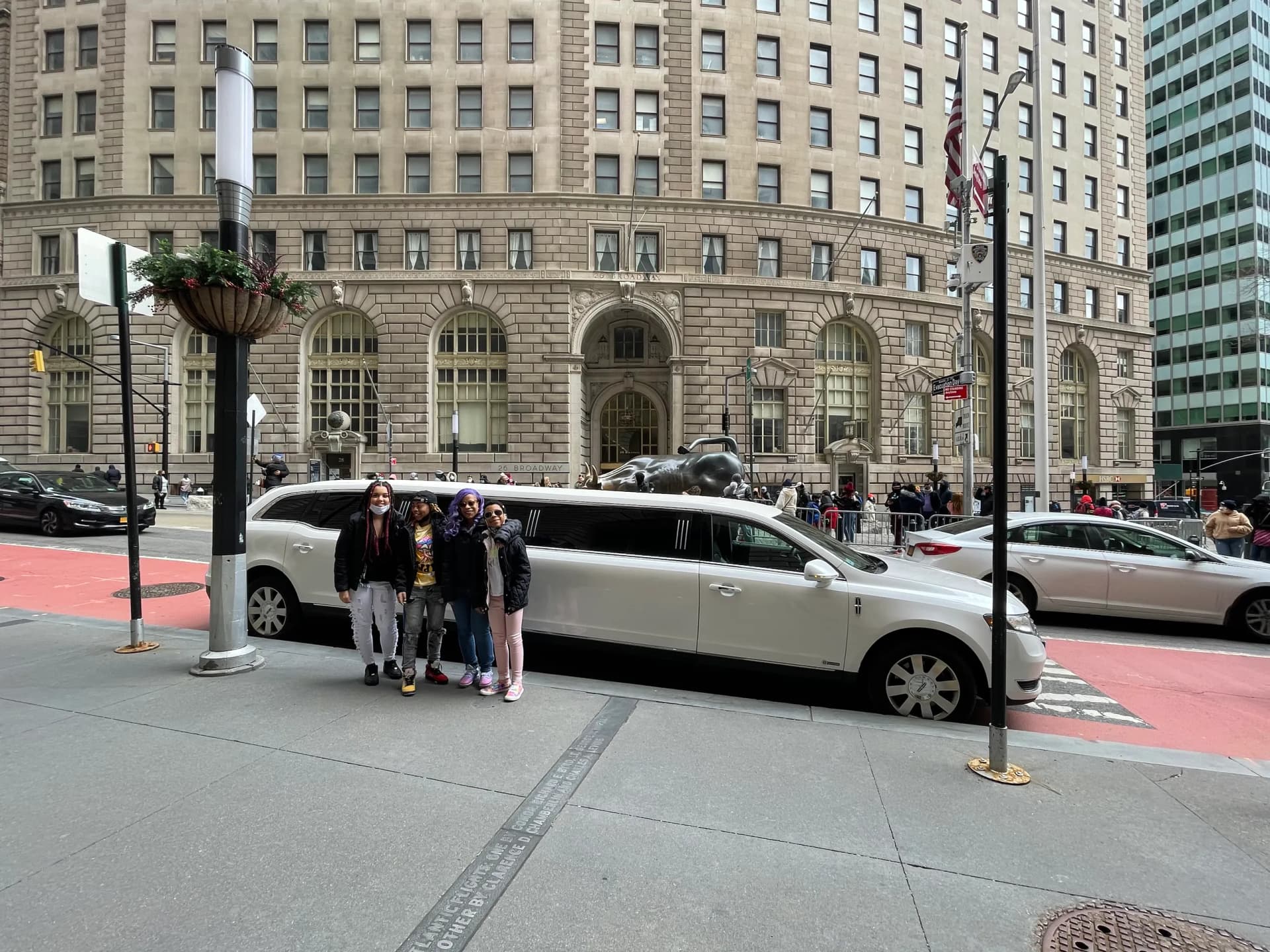 Group with a white stretch limousine near the Charging Bull on Wall Street