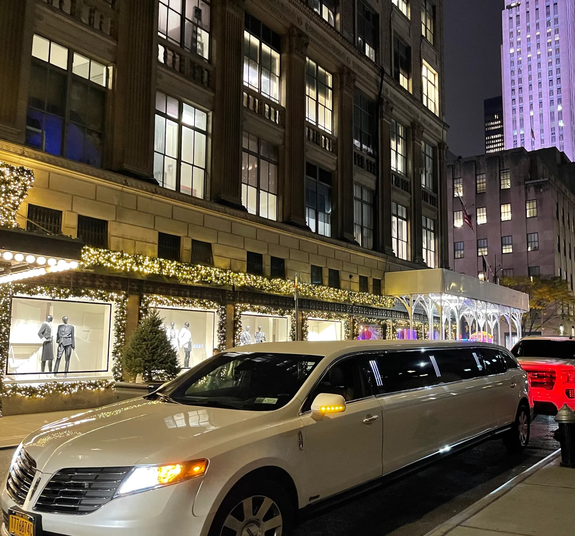 White stretch limousine passing holiday store windows near Rockefeller Center