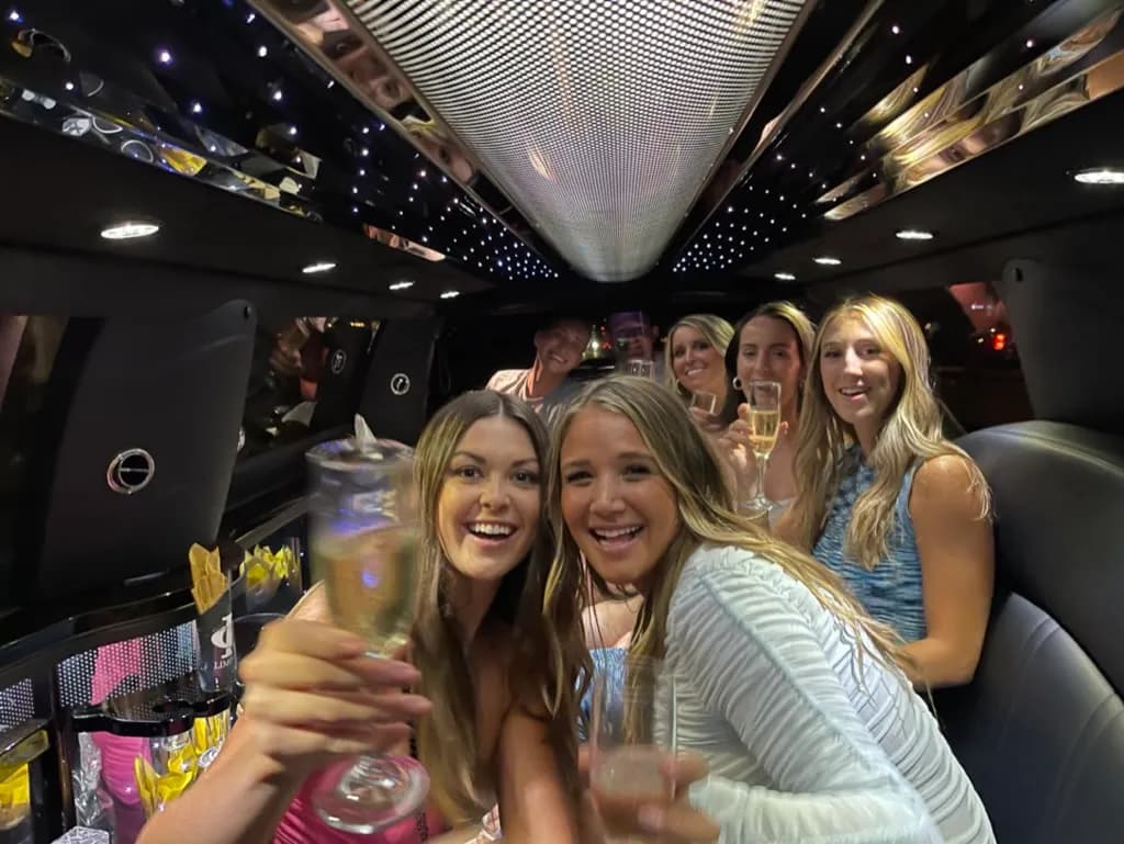 Bachelorette party friends raising champagne inside a stretch limousine