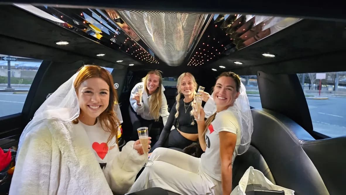 Bachelorette in a veil toasting with friends inside a stretch limousine