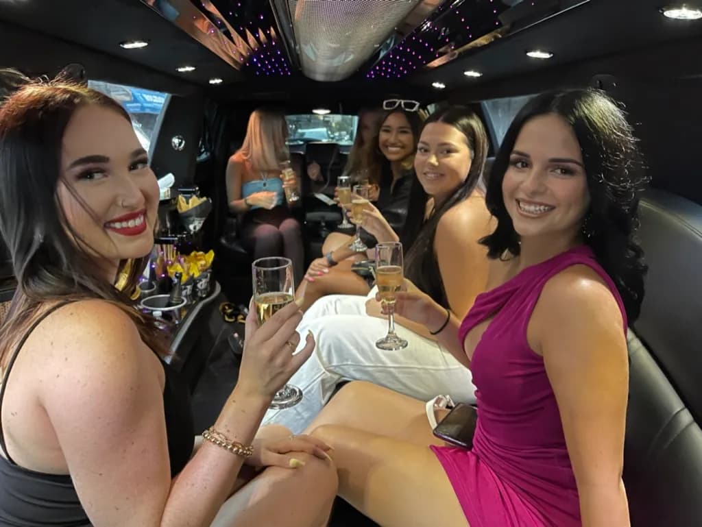 Friends in party outfits celebrating a birthday inside a stretch limousine