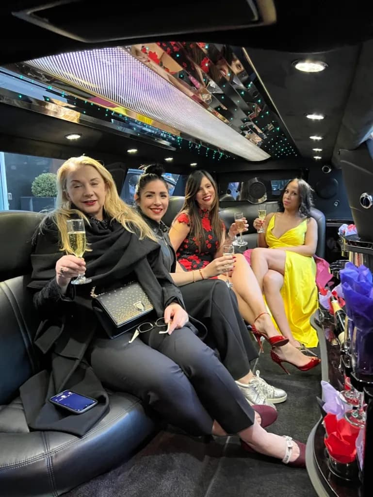 Guests in party dresses with champagne inside a stretch limousine