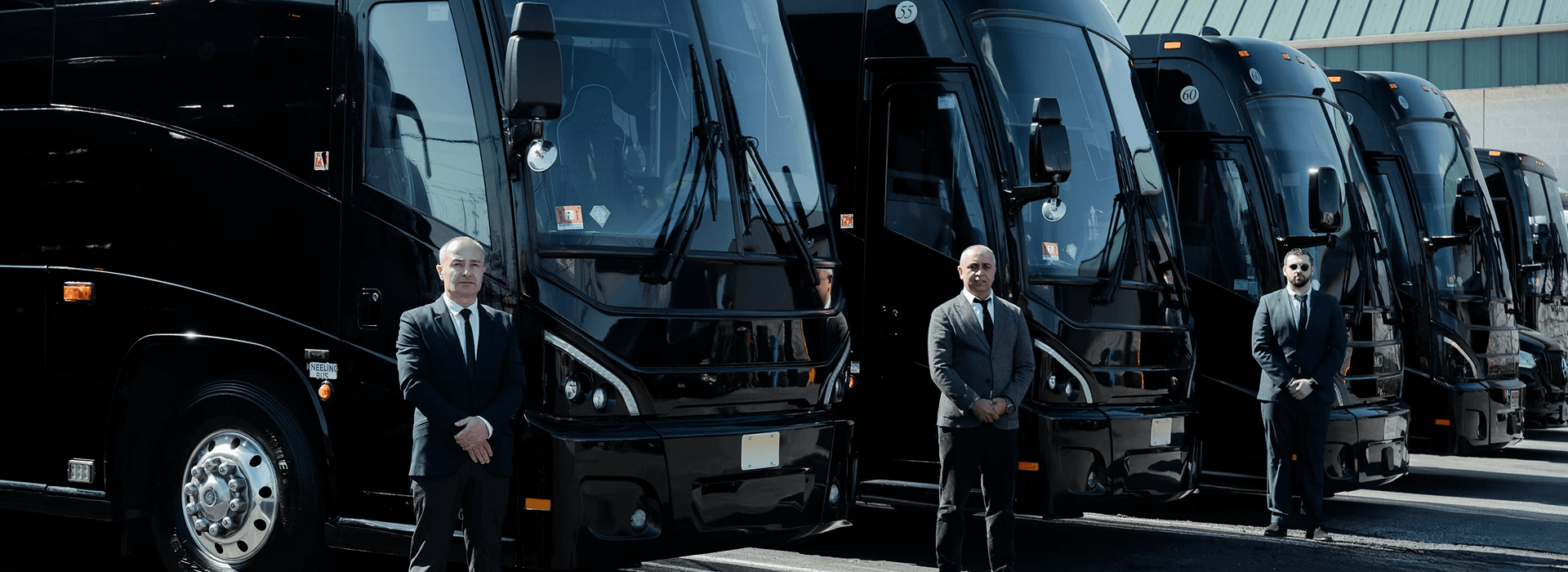 Chauffeurs standing in front of the King & Queen Limo motorcoach fleet