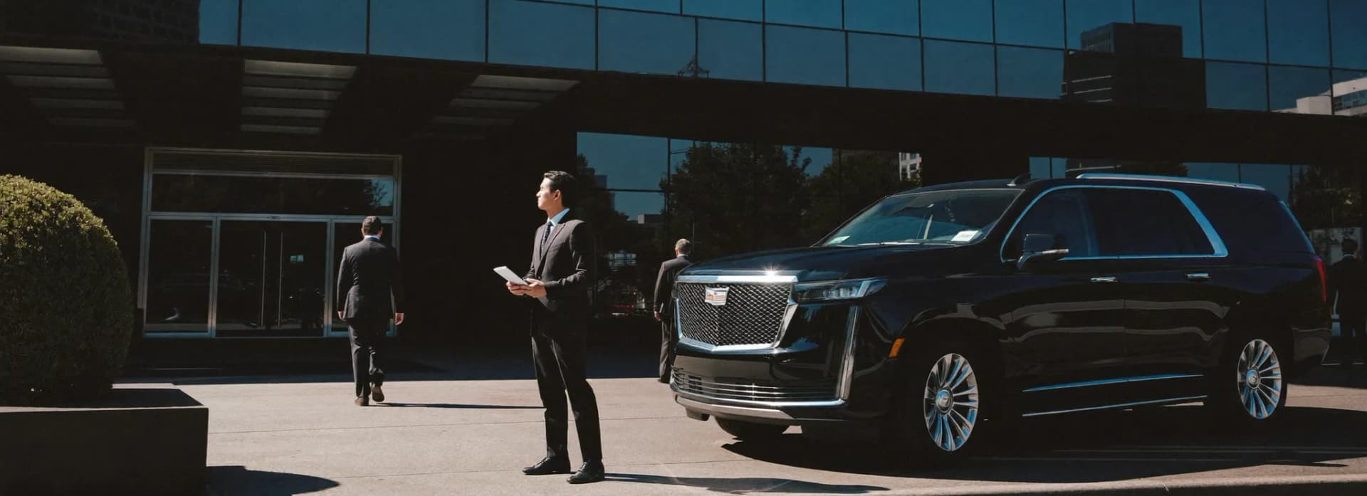 Executive entering a chauffeured black luxury sedan for a corporate pickup outside an office tower