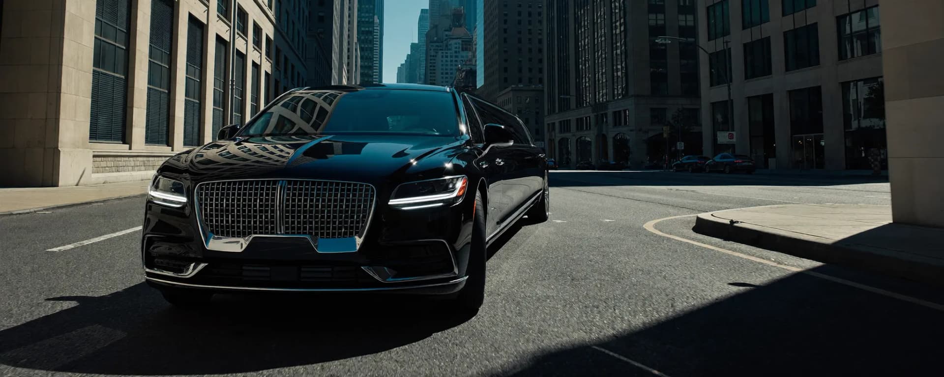 Black luxury chauffeured sedan waiting outside a Midtown Manhattan hotel for a limo service pickup