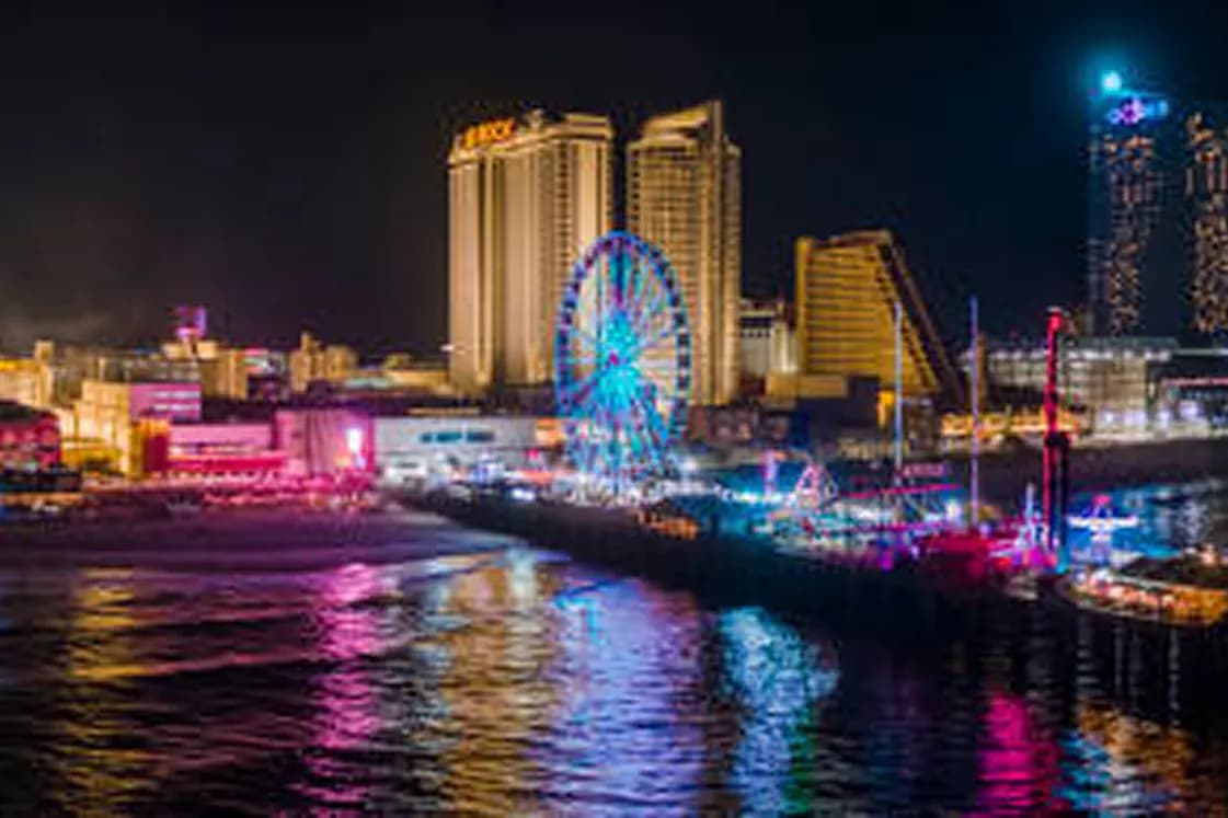 Atlantic City boardwalk at night with the lit Ferris wheel and casino towers