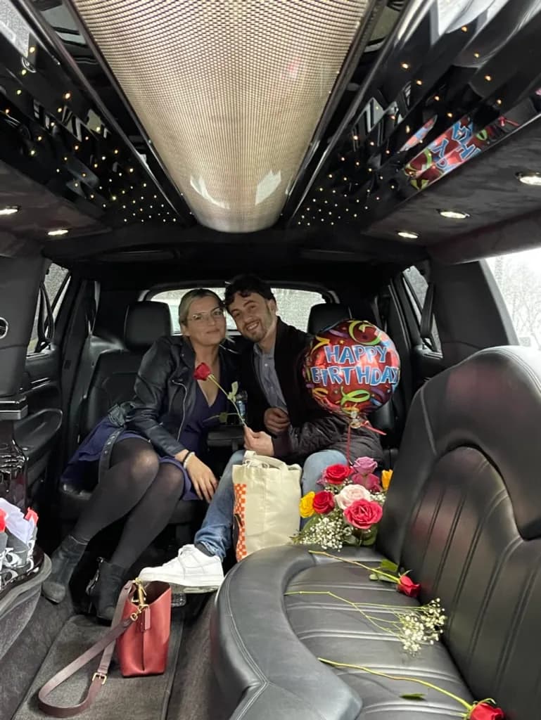Couple celebrating a birthday inside a stretch limousine with roses and a balloon
