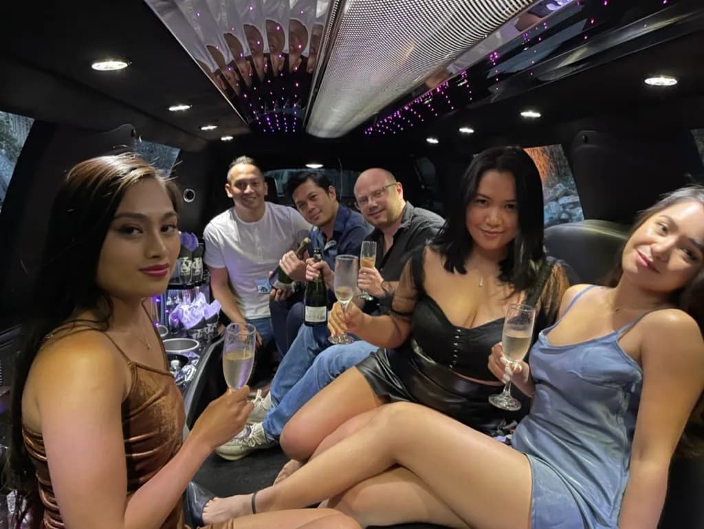 Friends celebrating with champagne inside a stretch limousine at night
