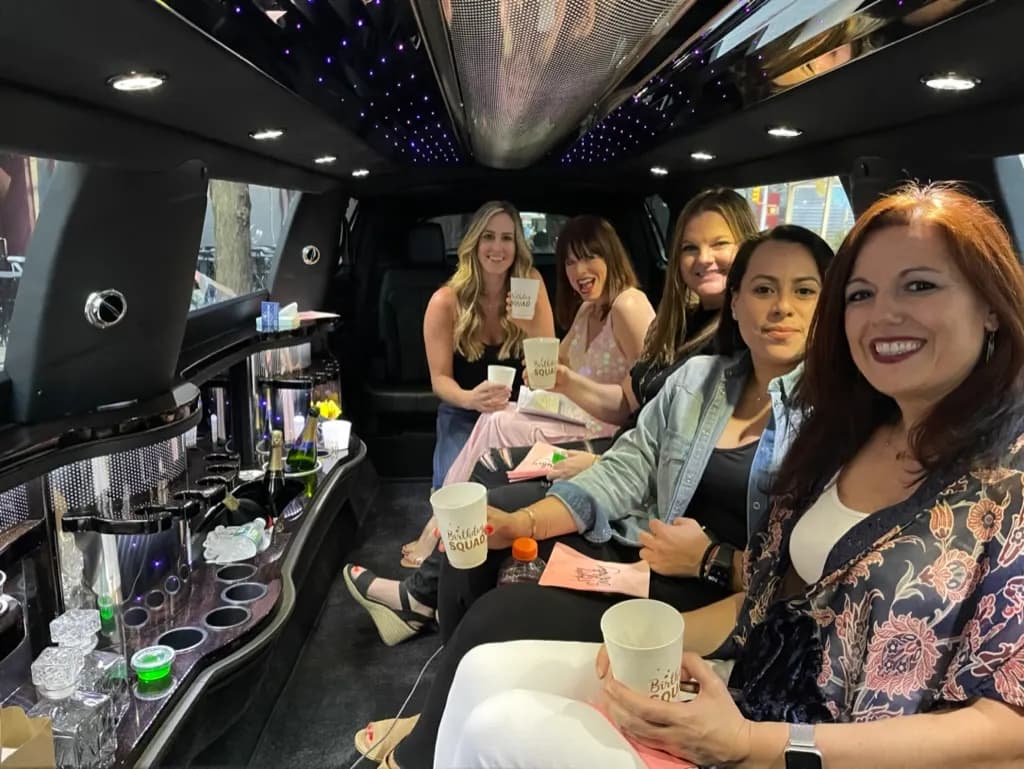 Friends celebrating a night out inside a stretch limousine with a lit bar