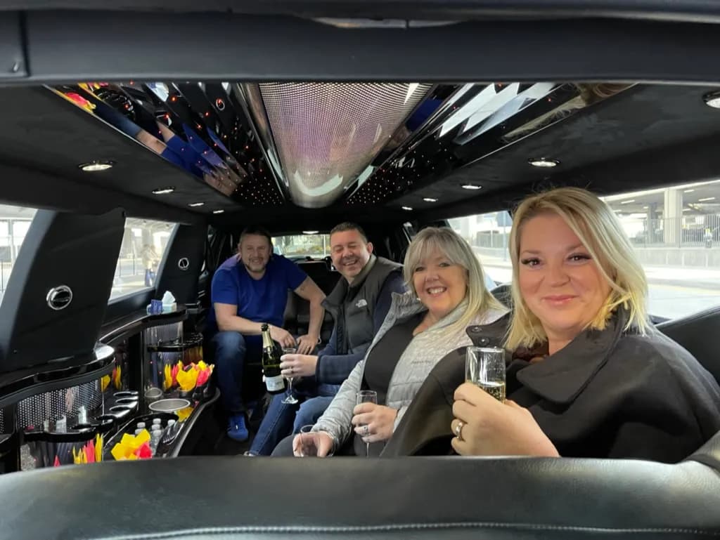 Group celebrating with champagne inside a stretch limousine with a starlight ceiling