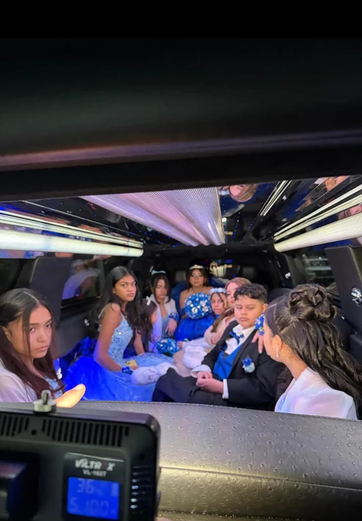 Quinceanera court in blue gowns riding inside an SUV stretch limousine