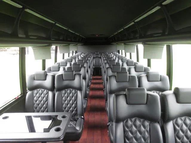 Coach bus interior with quilted black leather seats and a folding table