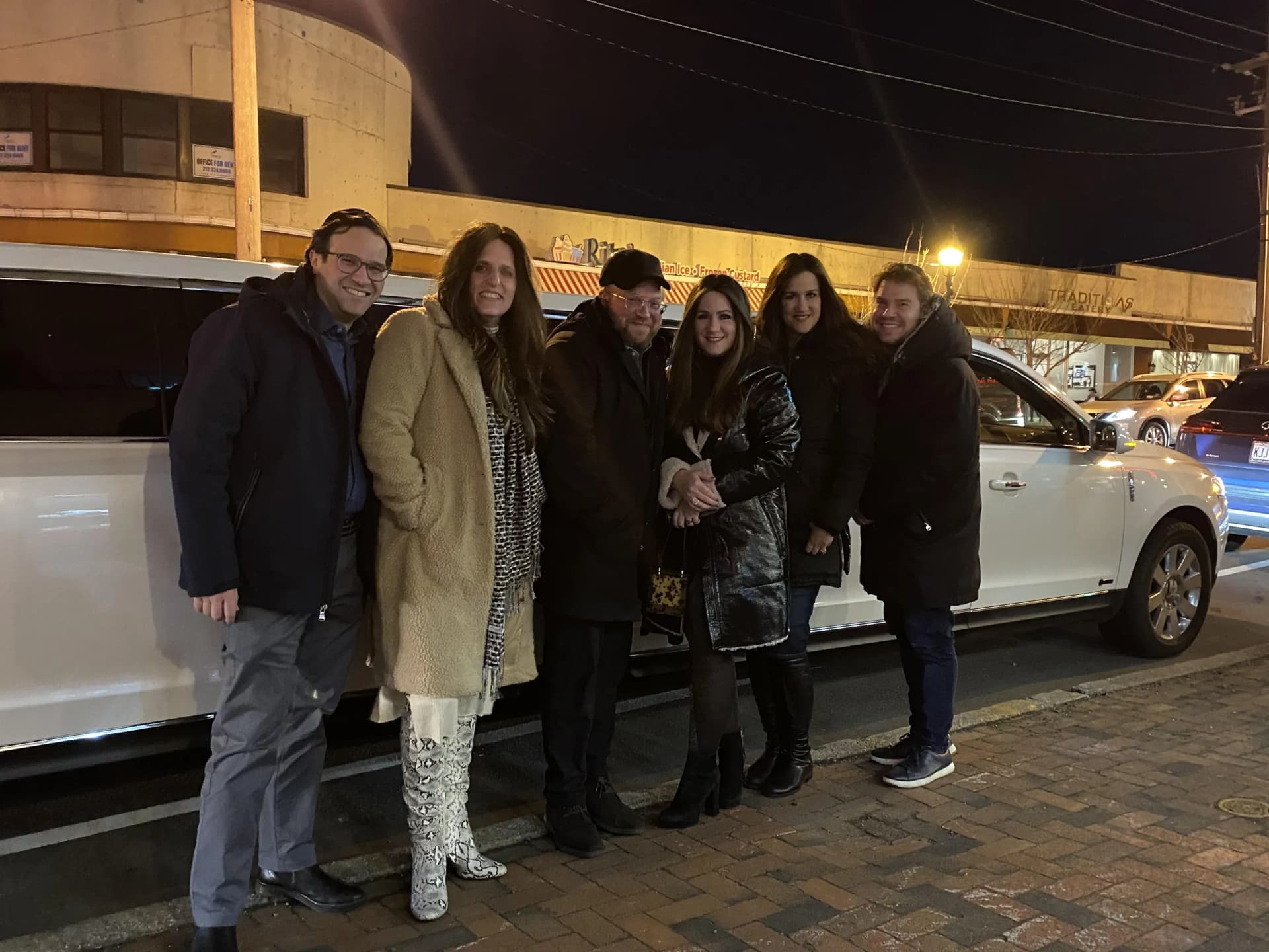 Group of friends on a night out beside a white Lincoln stretch limousine
