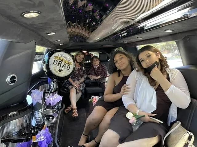 Graduates celebrating inside a stretch limousine with a Congrats Grad balloon