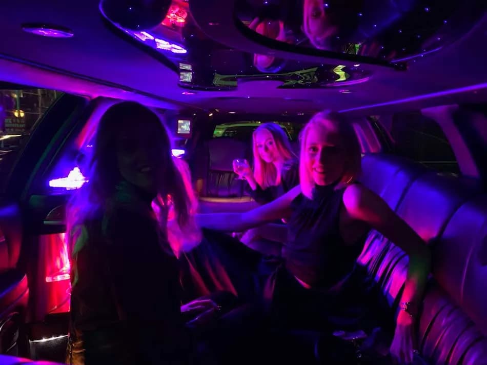 Friends inside a stretch limousine glowing with pink and purple LED lighting