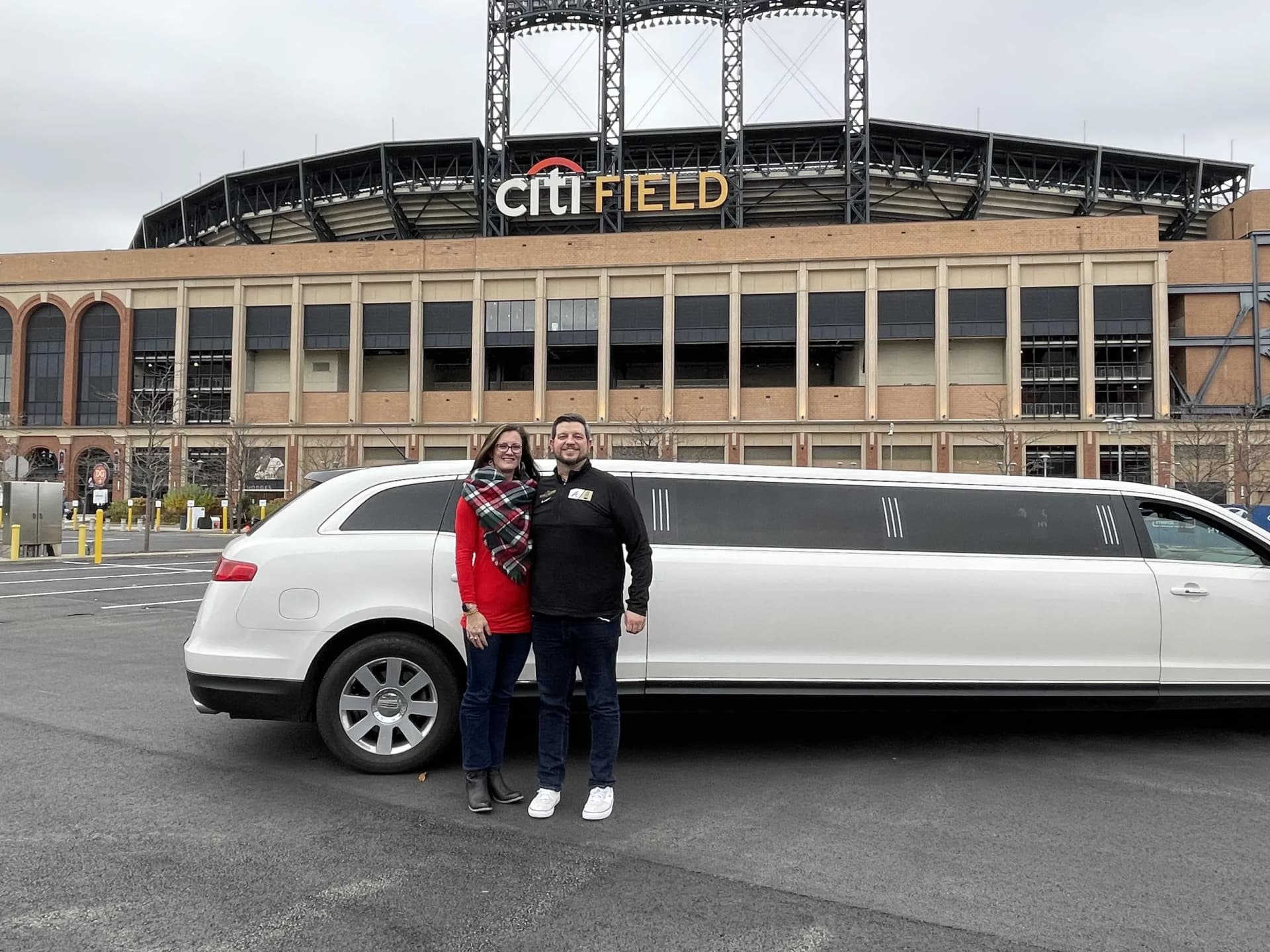 Couple with a white stretch limousine outside Citi Field