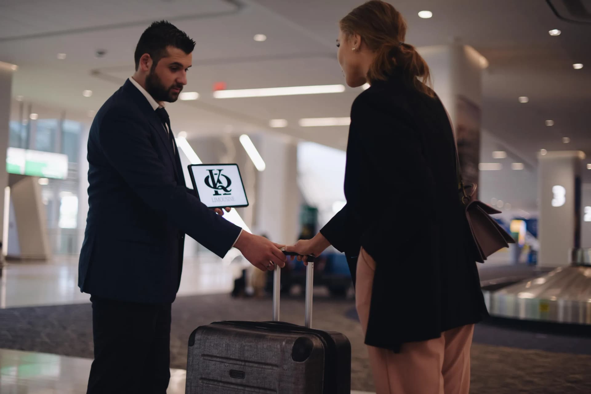 King & Queen chauffeur greeting a traveler with a tablet sign at baggage claim